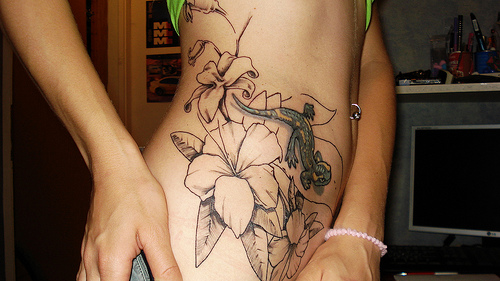 tatouage de fleurs et lézard sur la hanche